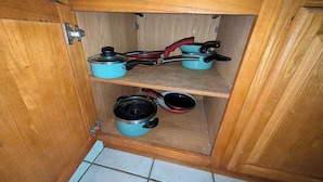 Ein Holzschrank mit drei Einlegebögen, auf jedem ein Topf.