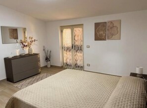 A bedroom with a large bed, a dresser, a mirror, and two doors. - Kalon Eidos. The magical place of Ionian Calabria (San Carlo-Condofuri Marina)
