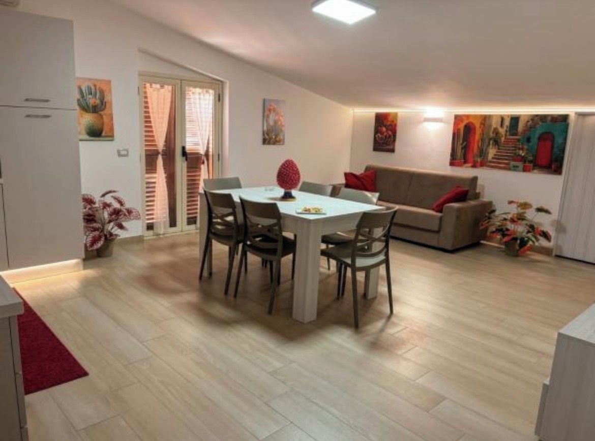 Un coin repas avec une table ronde et des chaises, un canapé et un tableau au mur.