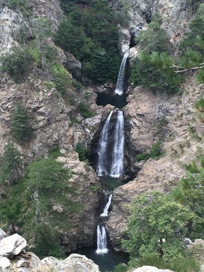 Une cascade à plusieurs niveaux dévalant une falaise rocheuse, le tout entouré d’une végétation luxuriante.