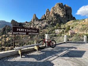 Une enseigne accueillante pour Pentedattilo Botteghie Artigiane, avec une vue sur les montagnes en arrière-plan.