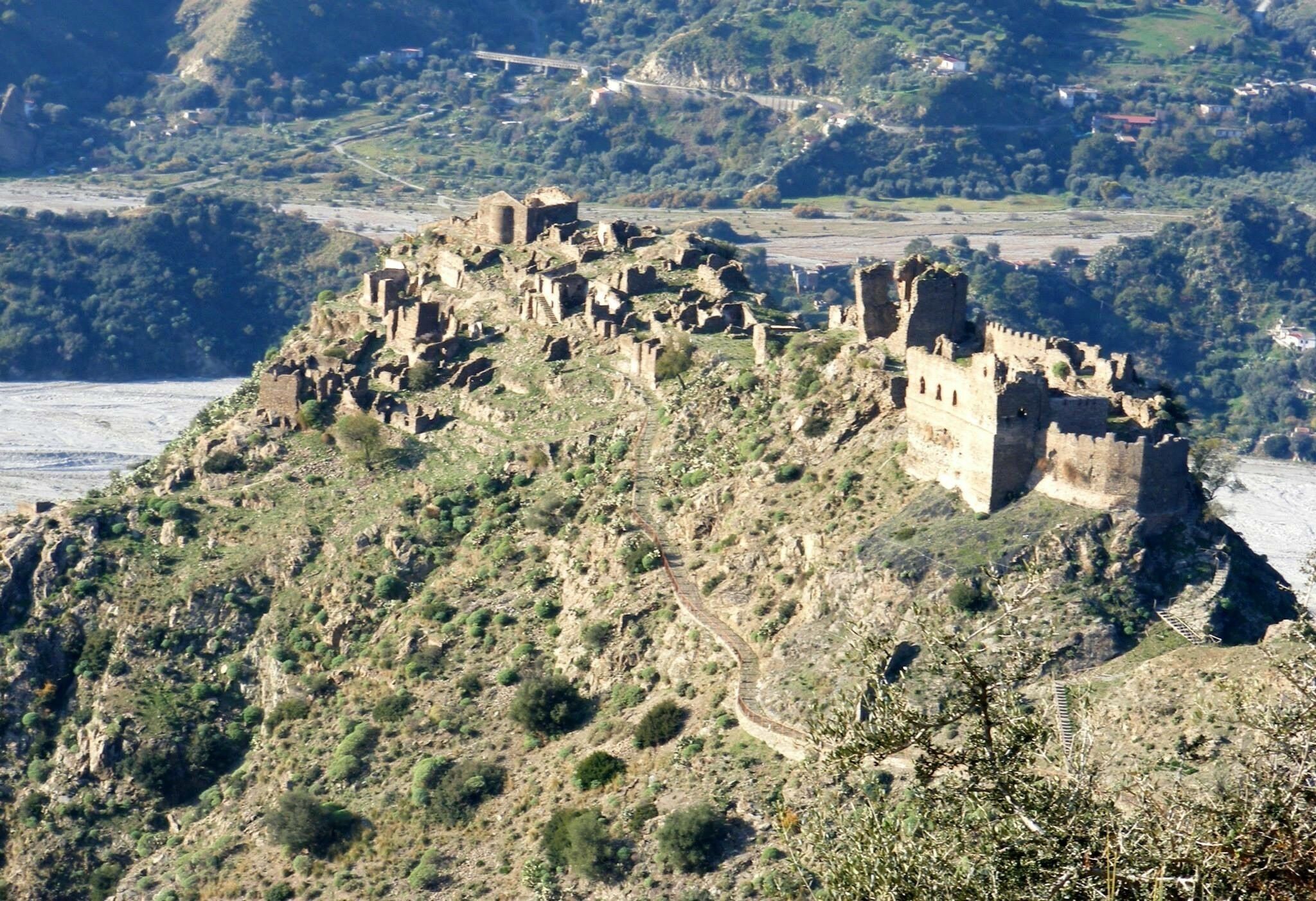 A historical castle on a hill with a winding path leading to it.