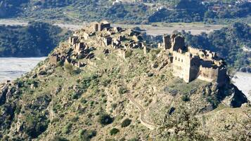 A historical castle on a hill with a winding path leading to it.