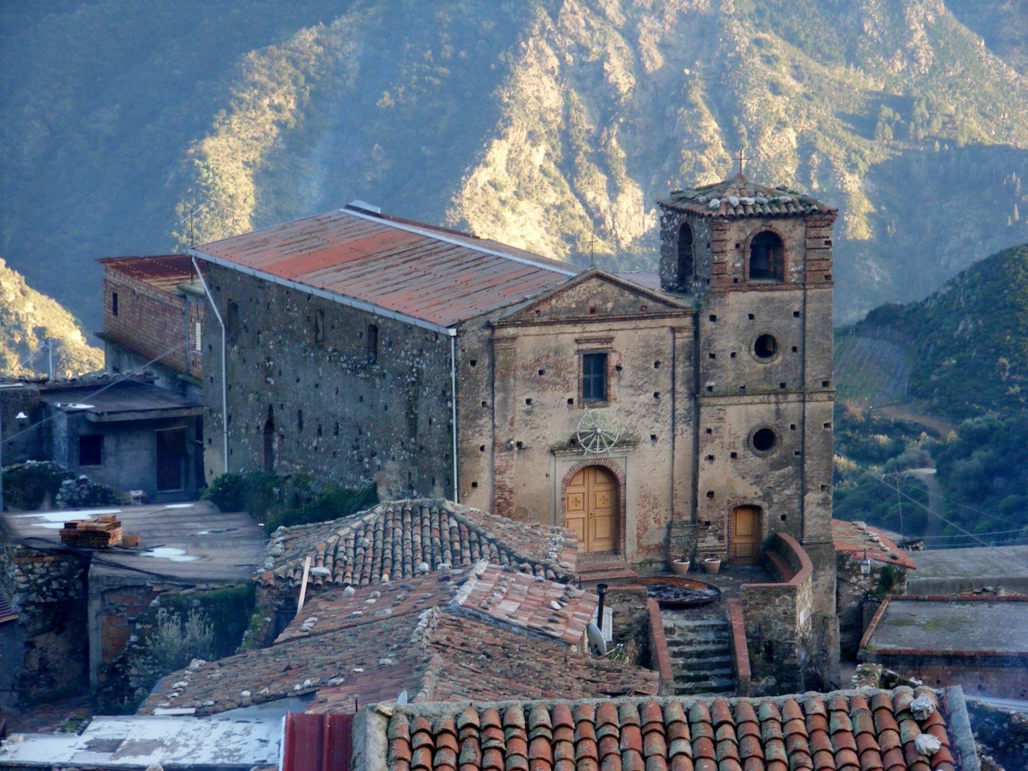 Un bâtiment historique doté d’un clocher, d’une cour et surplombant un paysage montagneux.