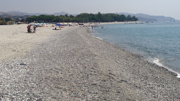 A pebbled beach with umbrellas and people. - Kalon Eidos. The magical place of Ionian Calabria (San Carlo-Condofuri Marina)