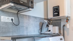 Una cocina compacta equipada con microondas, cafetera y lavadora.