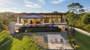 A modern house with a large patio, outdoor seating, and a swimming pool.