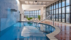 An indoor swimming pool with clear blue water, a curved edge, and a metal handrail. - Flat c Academia Sauna e Garagem - Jardim Paulista (São Paulo)