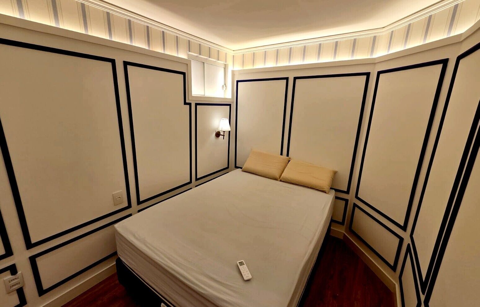 A bedroom with a large bed, a nightstand, and a wall-mounted lamp.