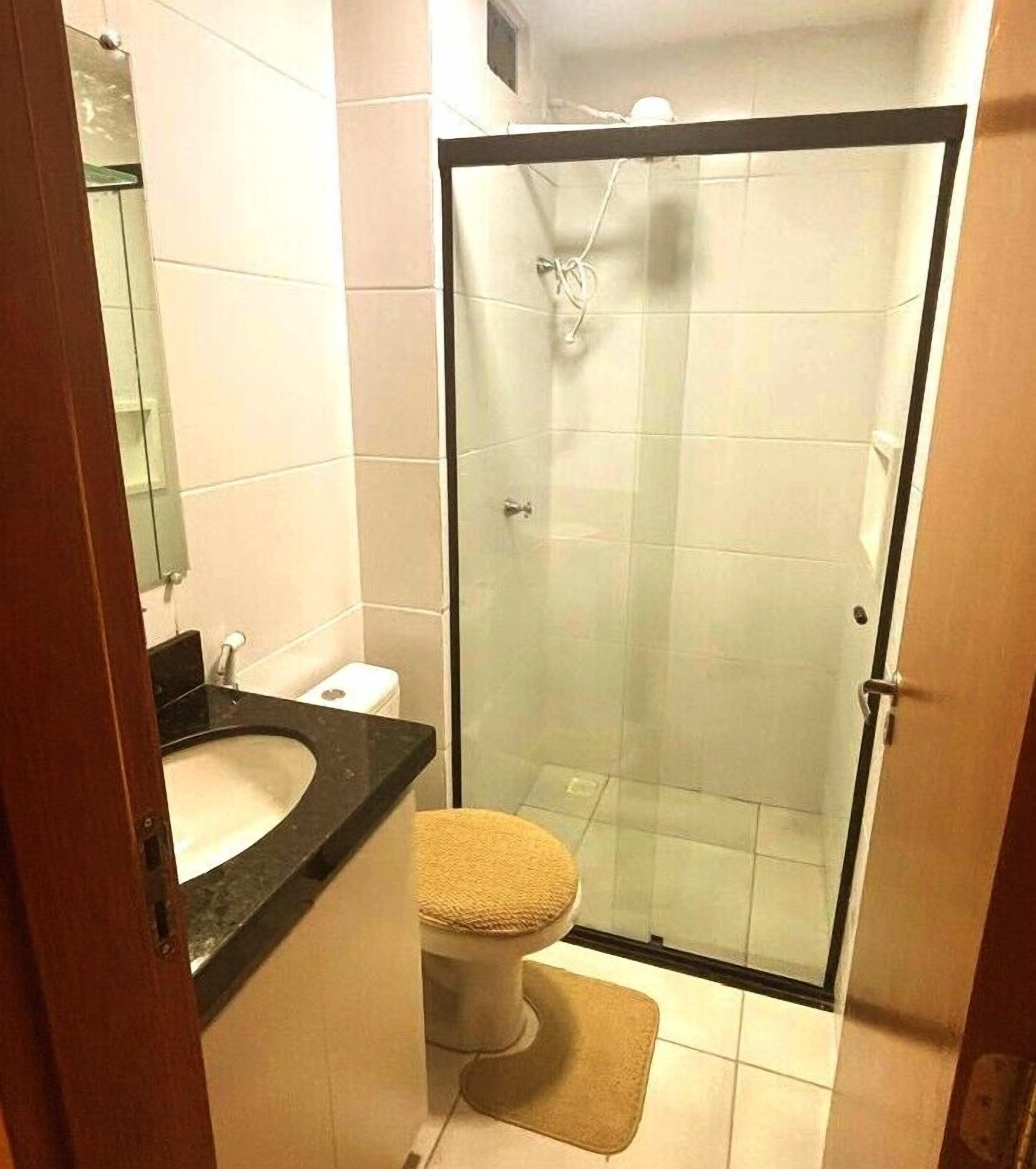 Une salle de bain avec une douche à parois de verre, des toilettes et un lavabo.