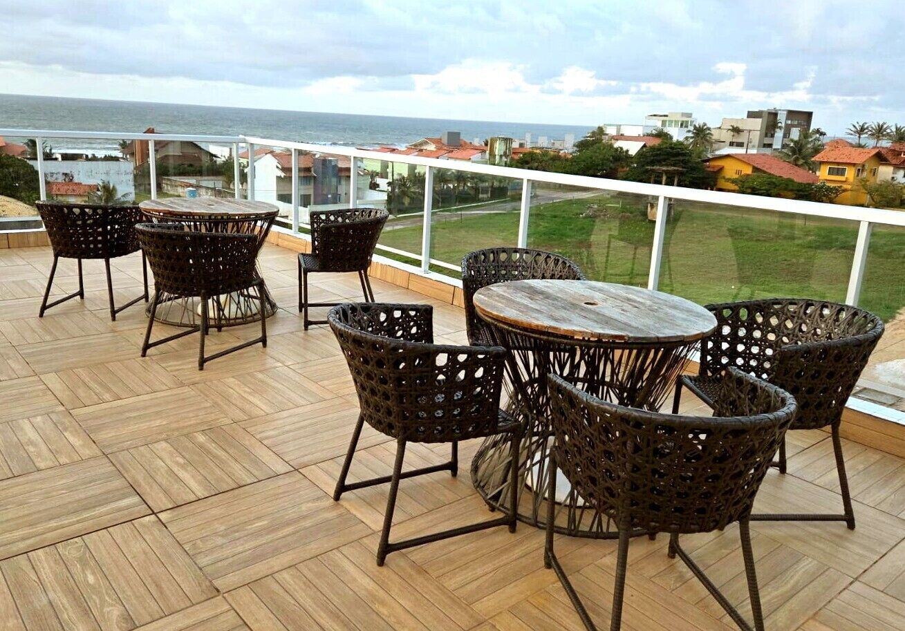 Een houten terras met rieten meubilair en uitzicht op zee.