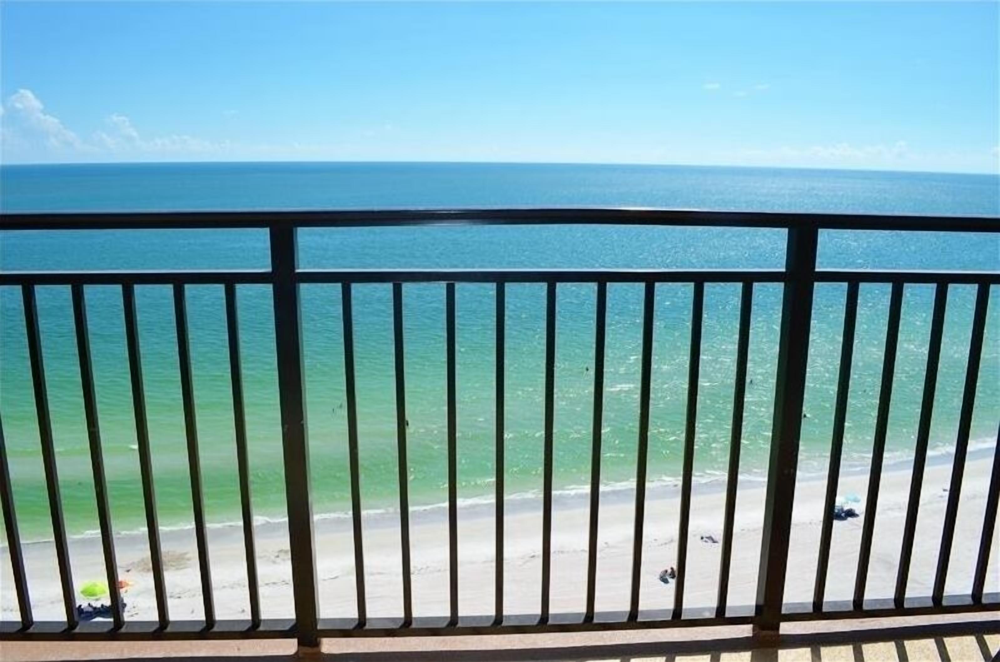 A balcony with a view of the ocean and beach.