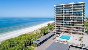 A multi-story hotel with a pool area, located near a beach with a clear view of the ocean. - Beachfront condo at Mansions (TREASURE ISLAND)