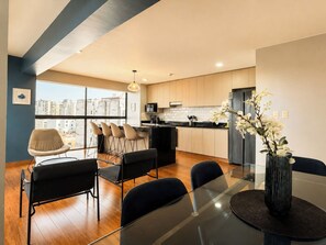 A modern kitchen with a dining area, large windows, and a city view. - Spacious & Modern Duplex in Miraflores (Lima)