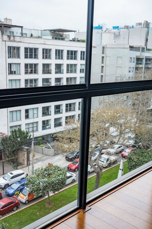 A view through a window of a multi-story building with a parking lot and trees in the foreground.