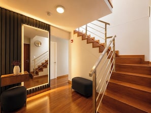 A modern interior with a wooden staircase, a bench, and a mirror. - Spacious & Modern Duplex in Miraflores (Lima)
