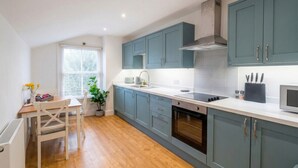A modern kitchen with grey cabinets, a white countertop, and a built-in oven. - Chic `Duke` Suite In Historic City Centre (Cambridgeshire)