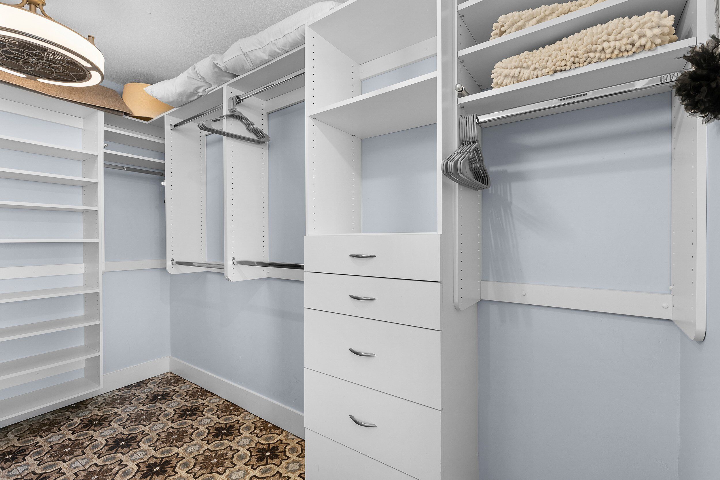A walk-in closet with open shelves, hanging space, and drawers.