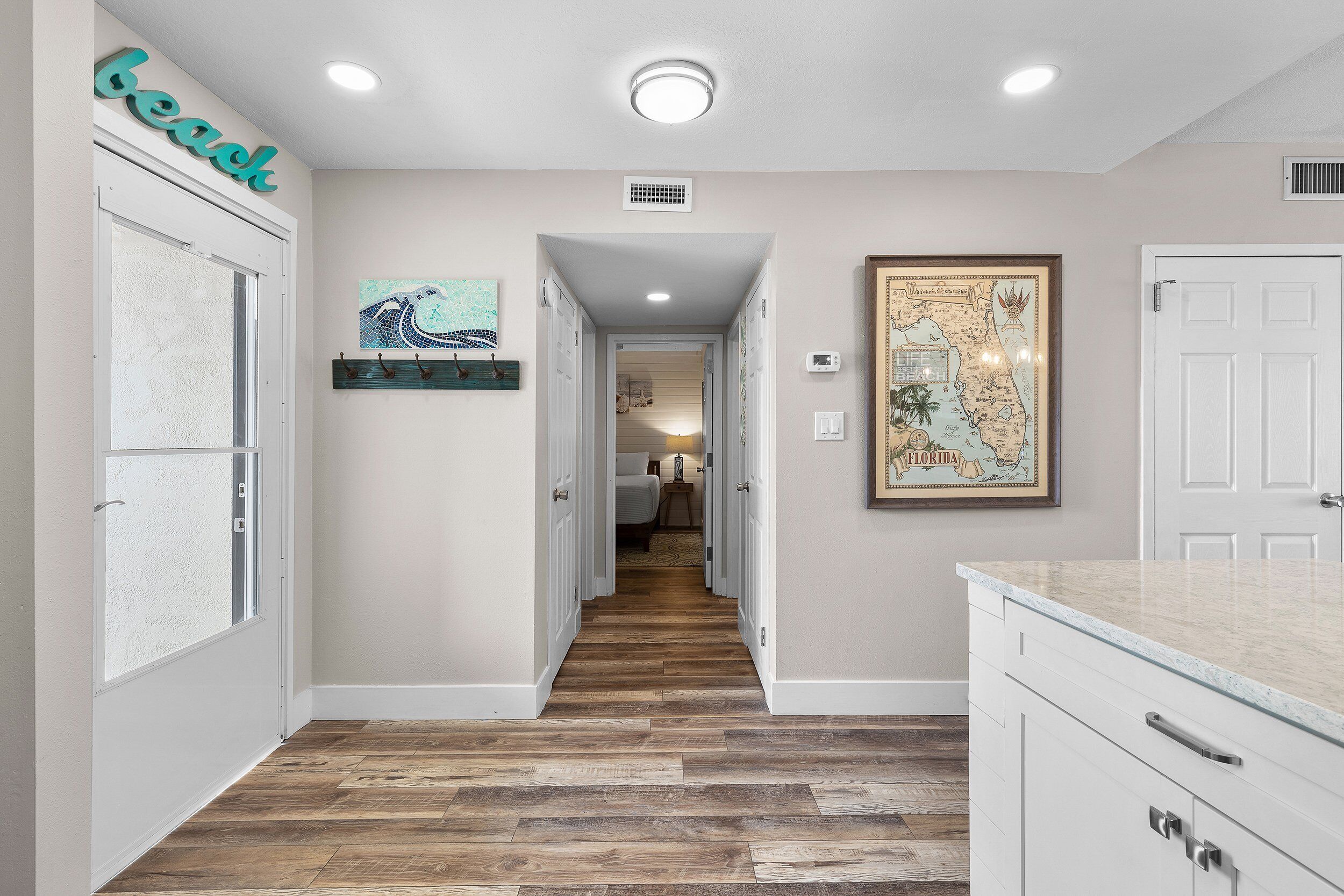 A hallway with wooden flooring, white walls, and a map on the wall.