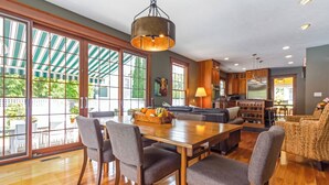 A spacious living area with a wooden dining table, grey upholstered chairs, and a large window with a view of greenery. - New Listing! Grand Getaway w/ Pool & Hot Tub (Douglas)