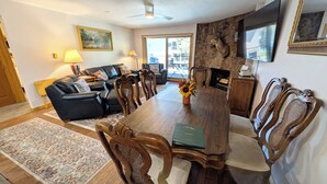 A dining area with a wooden table and chairs, a sofa, and a fireplace.