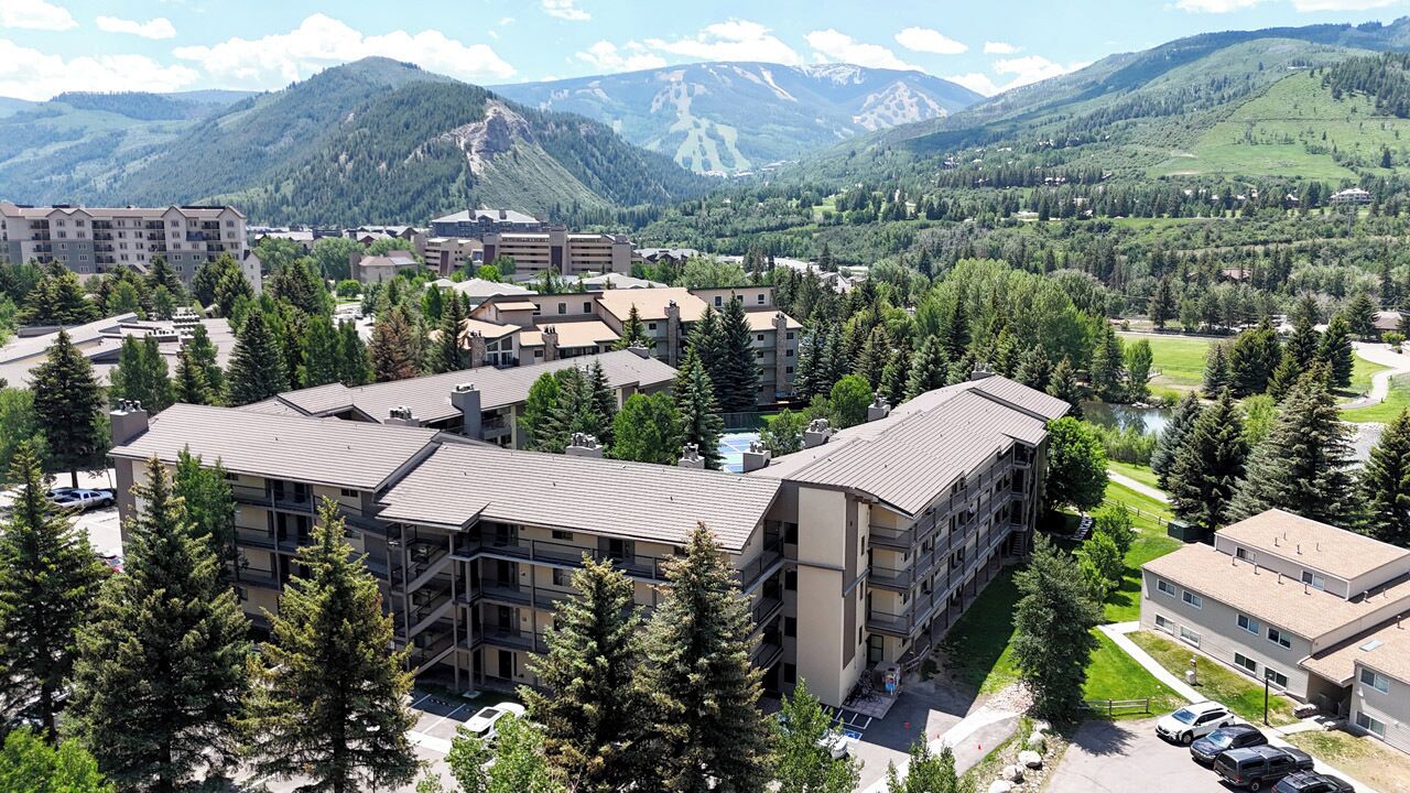 Un hôtel à plusieurs étages doté d’une cour intérieure, entouré d’arbres et avec des montagnes en toile de fond.