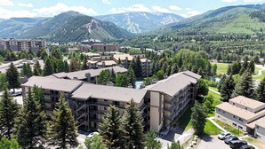 A multi-story hotel with a central courtyard, surrounded by trees and mountains in the background.
