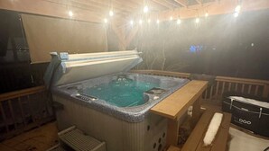 Un bain à remous sur une terrasse en bois, avec un banc et une table en bois.
