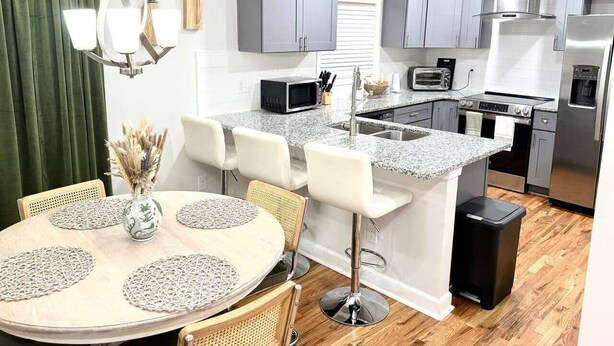 A modern kitchen with grey cabinets, a granite countertop, and stainless steel appliances. - Katie Mae’s Downtown Retreat (Atlanta)