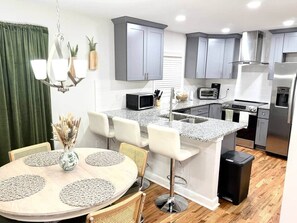 Une cuisine moderne avec des meubles gris, un plan de travail en granit et des appareils électroménagers en acier inoxydable.