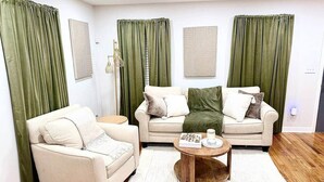 A living room with a beige sofa, a matching armchair, and a coffee table. - Katie Mae’s Downtown Retreat (Atlanta)