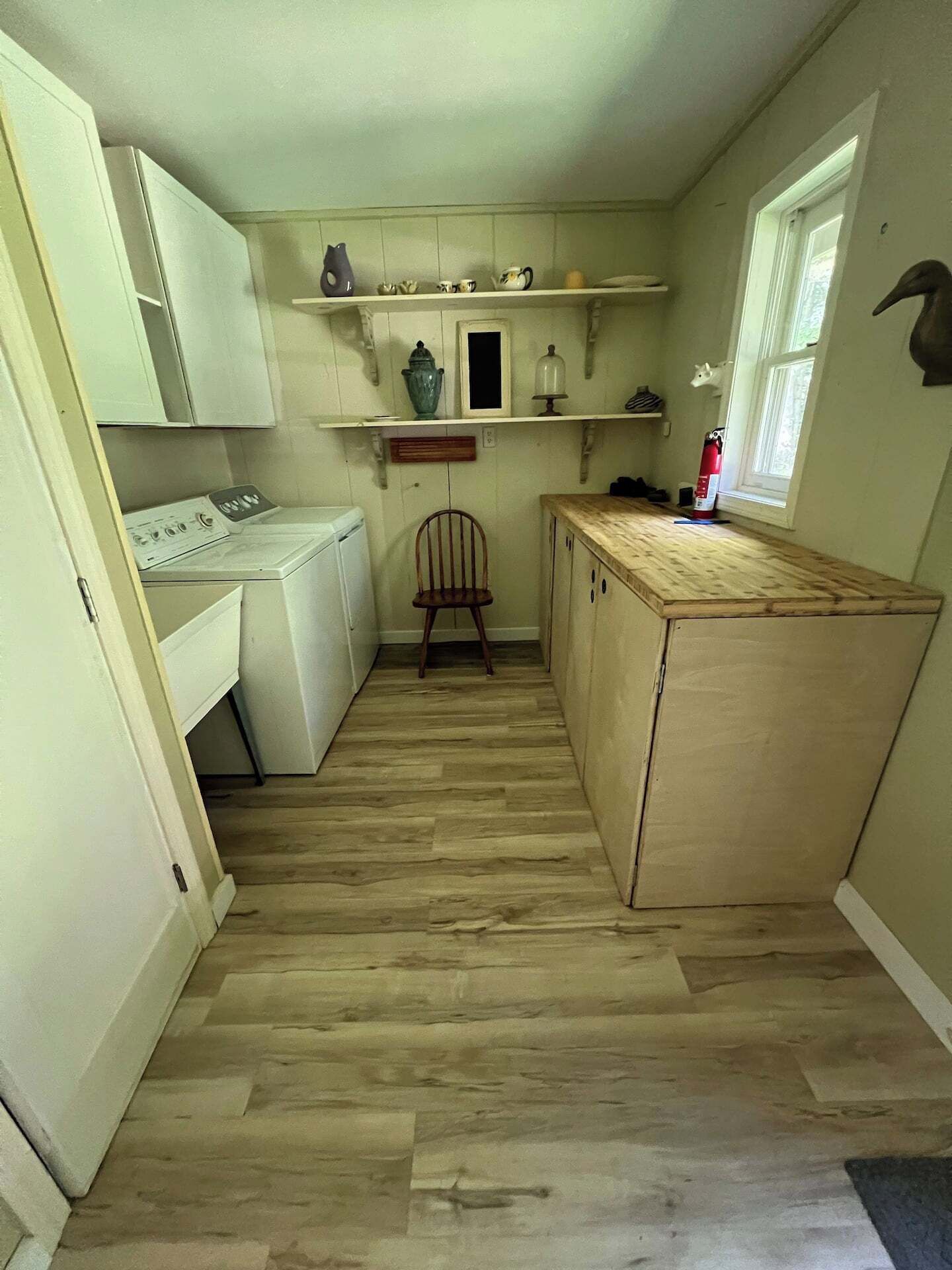 Une petite cuisine équipée d’un lave-linge, d’un plan de travail en bois et d’une chaise.