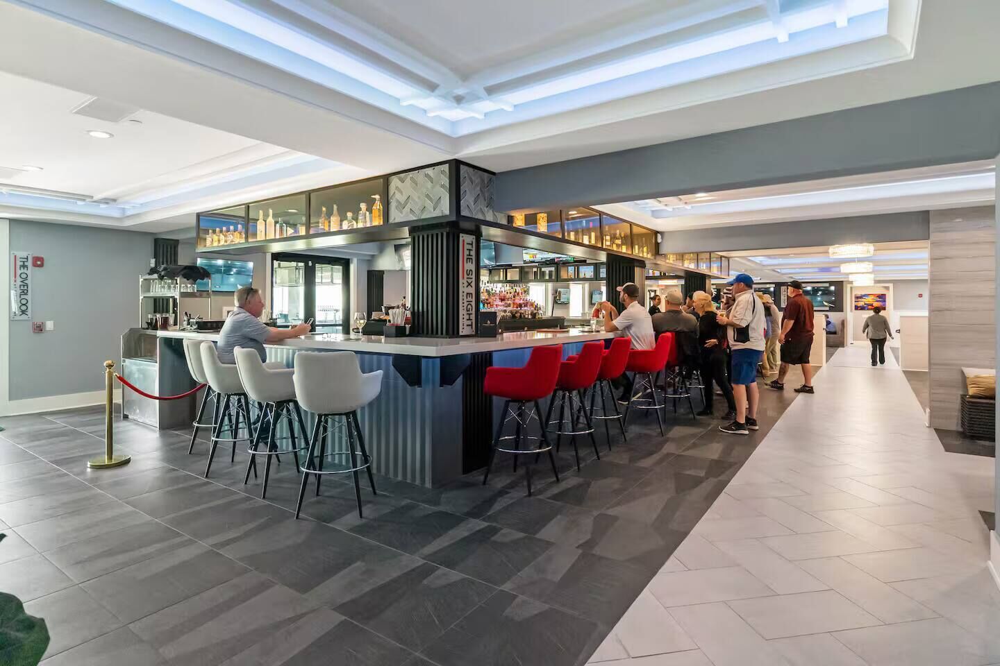 Uma área de bar moderna com balcão, banquetas e diversas garrafas.