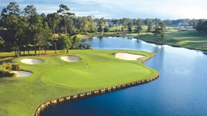 Un parcours de golf doté de bunkers, d’un plan d’eau et entouré d’arbres.