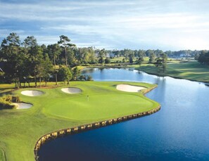 Un parcours de golf doté de bunkers, d’un plan d’eau et entouré d’arbres.