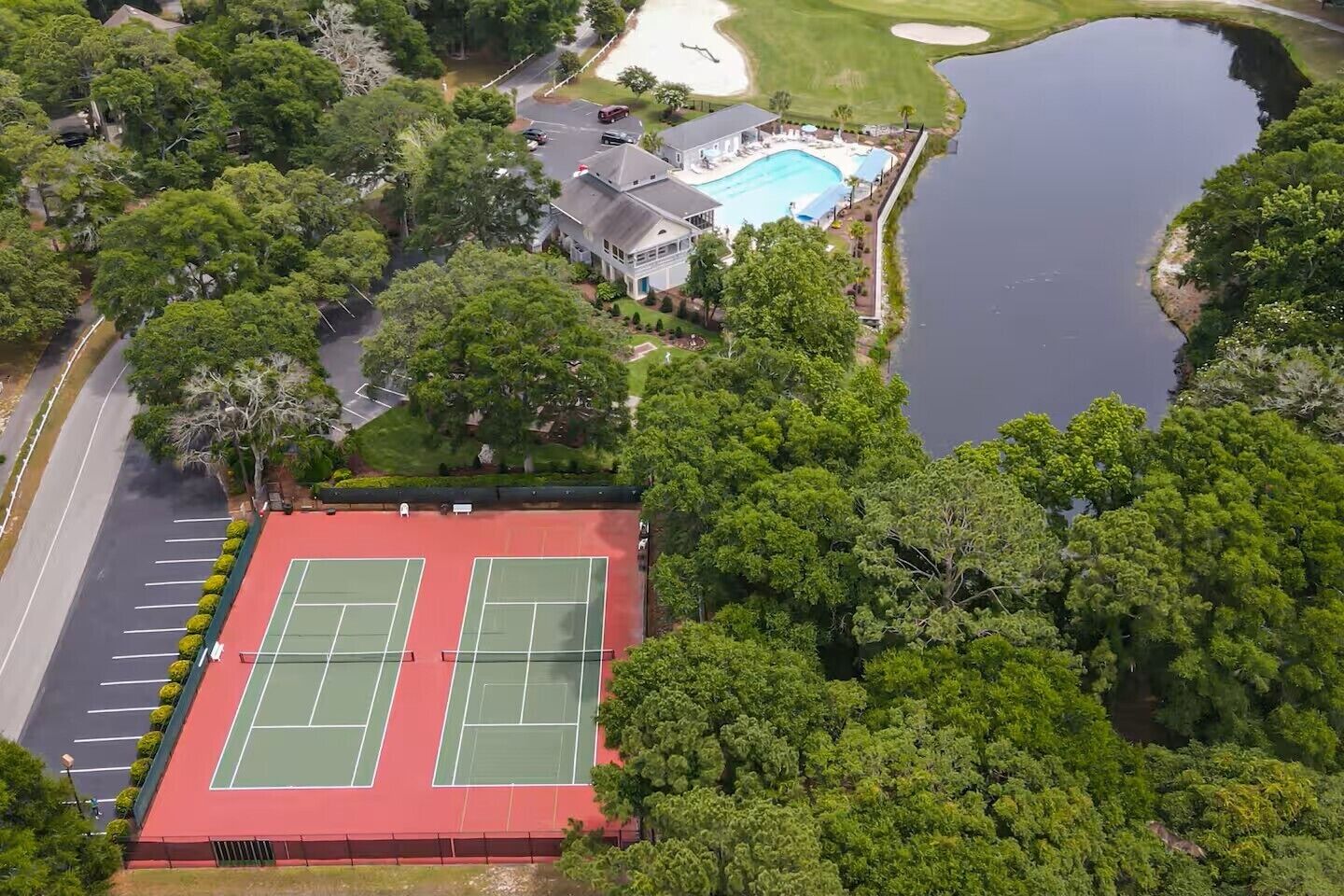 Vue aérienne d’une propriété comprenant un court de tennis, une piscine et un terrain de golf.