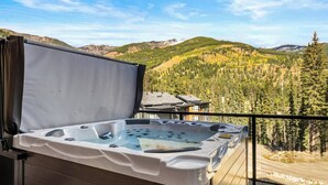Un jacuzzi en un balcón con una vista panorámica de las montañas.
