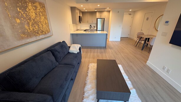 Una sala de estar moderna con un sofá oscuro, un tapete mullido blanco y una mesa de centro de madera.