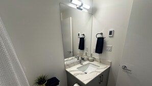 Un baño moderno con un lavamanos blanco, un espejo grande y un perchero para toallas.