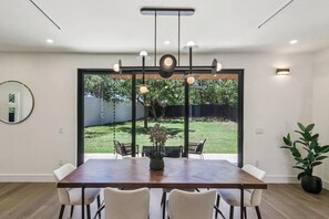 A dining area with a large table, chairs, and a hanging light fixture. - Upscale Austin Getaway w/ Designer Interiors (Austin)