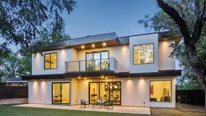 Una casa moderna de dos pisos con ventanas amplias, un balcón y un interior luminoso.