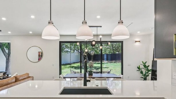 Una cocina moderna con una isla central, luces colgantes y vistas al exterior.