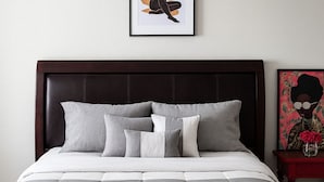 A neatly made bed with a grey and white duvet, a dark headboard, and a framed artwork above it. - Spacious Cedar Park Retreat (Cedar Park)