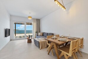 A modern living room with a dining area, a sofa, and a view of the sea. - Roos Villas Naxos - Villa I (Naxos)
