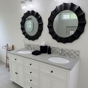 A bathroom with two round mirrors, a double sink vanity, and a towel rack. - Spacious Cedar Park Retreat | Backyard Oasis (Cedar Park)