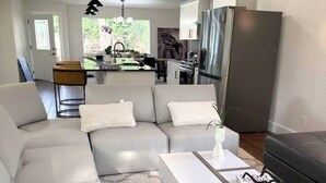 Un salon moderne avec un canapé d’angle, une table basse et une petite table d’appoint agrémentée d’une plante.