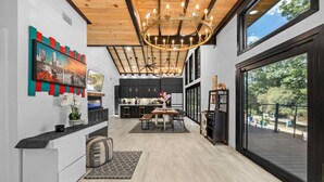 A modern kitchen with a dining area, large windows, and a wooden ceiling. - Spectacular Grand Getaway - Pool • Fire Pit • Bar (Austin)