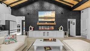 A modern living room with a fireplace, white furniture, and a black textured wall. - Spectacular Grand Getaway - Pool • Fire Pit • Bar (Austin)