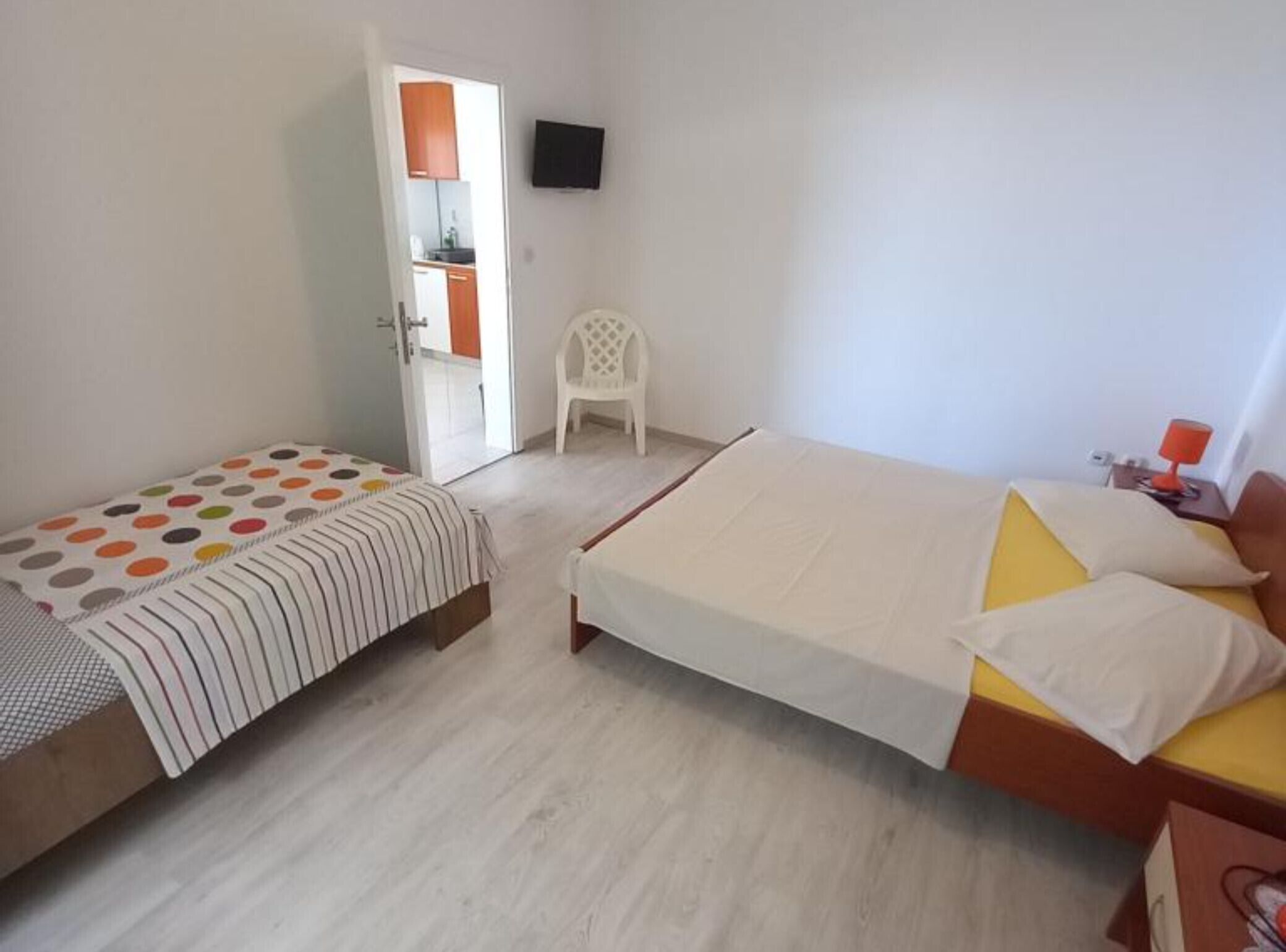 Un dormitorio con dos camas, un televisor en la pared y una silla.