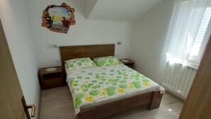 Een slaapkamer met een houten bed, een nachtkastje, een wandklok en een raam met gordijnen.